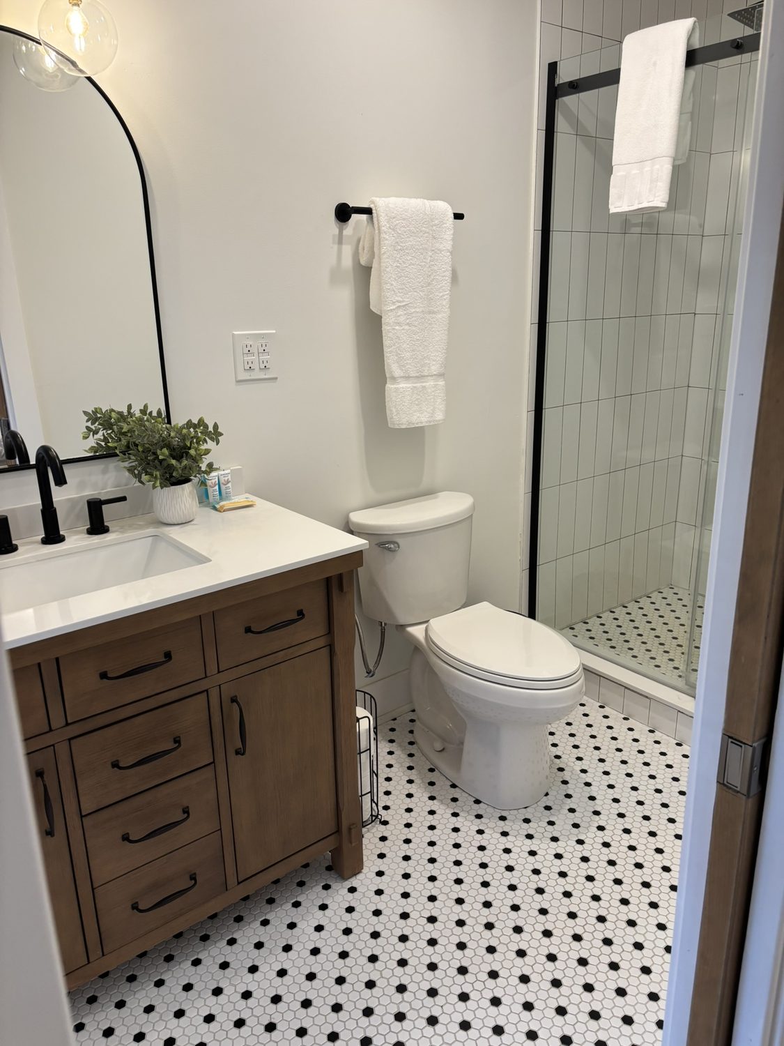 Bathroom with wood vanity, arched mirror and glass walk-in shower
