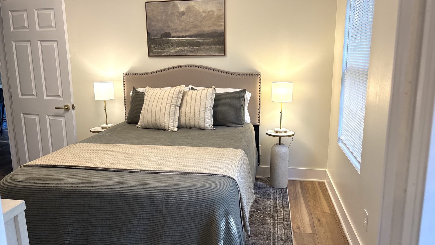 Second bedroom — queen bed with an upholstered headboard, matching lamps, a runner across the foot and a patterned rug
