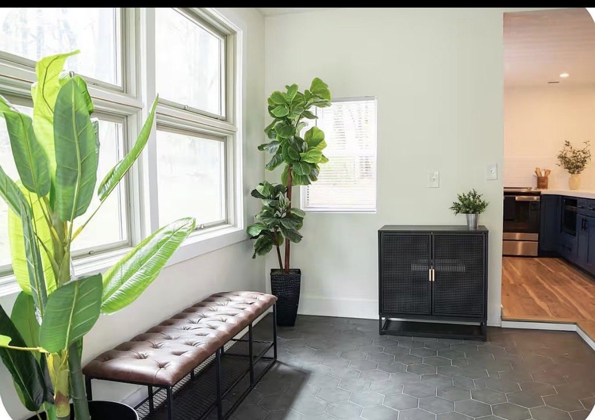 Entry with a leather bench, potted plants and a view through to the kitchen