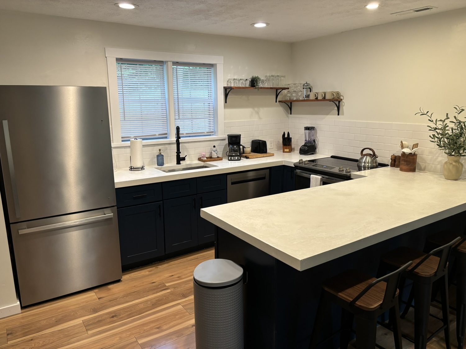 Kitchen with stainless refrigerator, navy island and bar stools